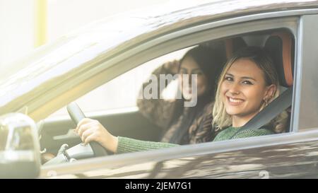 Zwei junge Frauen lächeln in einem Auto genießen ein Straßenfahrkonzept Best Friends Forever Stockfoto