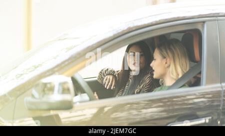 Zwei junge Frauen lächeln in einem Auto genießen ein Straßenfahrkonzept Best Friends Forever Stockfoto