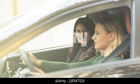 Zwei junge Frauen lächeln in einem Auto genießen ein Straßenfahrkonzept Best Friends Forever Stockfoto