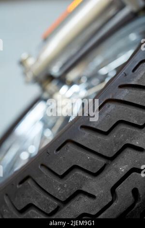 Nahaufnahme geneigte Ansicht eines Motorradreifens. Reifen für benutzerdefinierte moderne Sportfahrrad entwickelt. Aufhängung am klassischen Motorrad-Vorderrad. Wartung ein Stockfoto