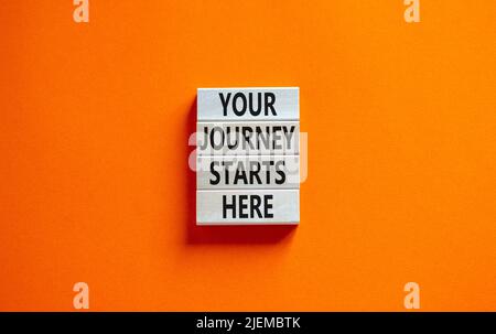 Ihre Reise beginnt hier Symbol. Konzeptworte Ihre Reise beginnt hier auf Holzblöcken auf einem wunderschönen orangen Tisch mit orangefarbenem Hintergrund. Business, moti Stockfoto