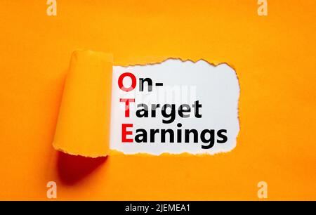 OTE-Symbol für die angestrebten Gewinne. Das Konzept formuliert die Zielgewinne des OTE auf einem Weißbuch auf einem schönen orangen Hintergrund. Geschäft und OTE auf Zielvorgabe Stockfoto