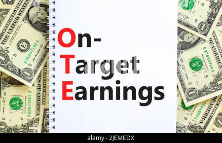 OTE-Symbol für die angestrebten Gewinne. Das Konzept formuliert OTE-Zielgewinne auf weißer Note auf einem schönen Hintergrund von Dollarnoten. Business und OTE on-tar Stockfoto