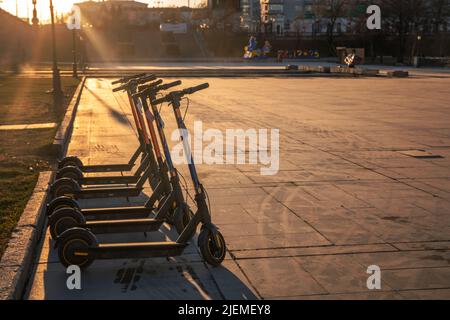 Elektroroller steht bei Sonnenaufgang auf der Straße Stockfoto