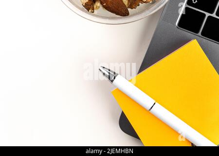 Weißer Schreibtisch mit Stift, bunten Aufklebern, Laptop und anderen Büroartikeln. Stockfoto