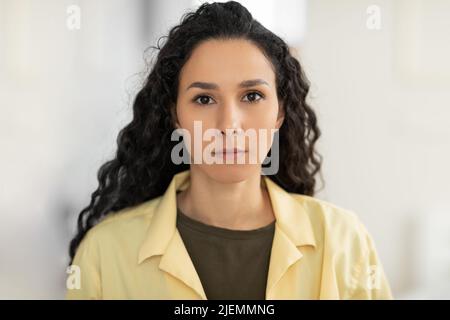 Porträt einer fokussierten jungen lateinischen Frau in legerer Kleidung, die zu Hause die Kamera anschaut Stockfoto