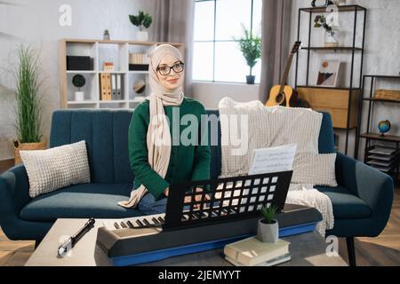 Muslimischer Musiklehrer leitet eine Lektion über das Spielen eines Musikinstruments über das Internet. Klavierunterricht online und Online-Musikunterricht während der Quarantäne für die Coronavirus-Pandemie. Stockfoto