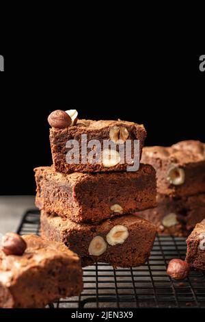 Schokoladen-Brownies mit Nüssen auf Kühlgestell auf dunklem Hintergrund, Textraum. Vertikale Ausrichtung Stockfoto