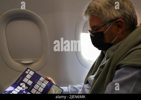 Älterer Mann im Flugzeug, der die Notfallanweisungen überprüft Stockfoto