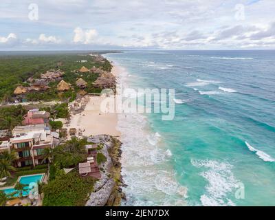 Luftaufnahme des weißen Sandstrandes von Tulum mit Wellen des Karibischen Meeres und Hotelkabinen an der Küste Stockfoto