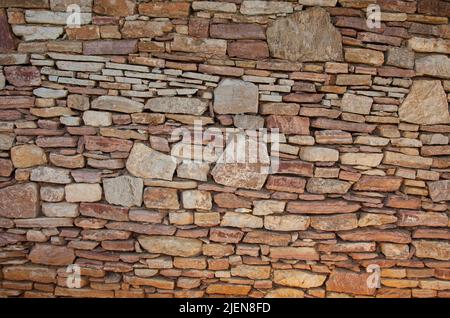 Eine andere Steinwand besteht aus Steinen unterschiedlicher Größe. Asymmetrische Steinwand. Stockfoto