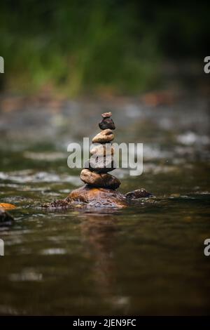 Steine sorgfältig auf sanft fließenden Fluss gestapelt Stockfoto