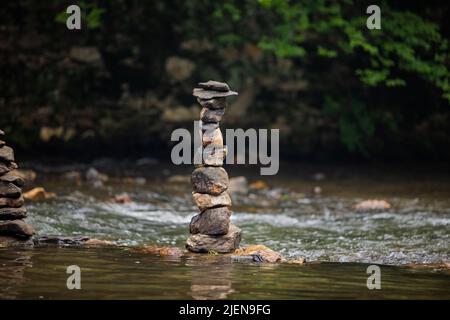 Steine sorgfältig auf sanft fließenden Fluss gestapelt Stockfoto