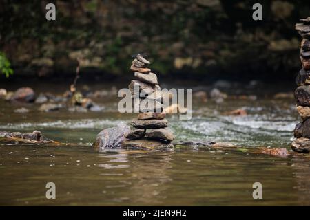 Steine sorgfältig auf sanft fließenden Fluss gestapelt Stockfoto