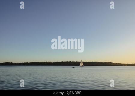 Ruhige Szene mit Segelboot und Kajak auf dem Wasser bei Sonnenuntergang auf dem Fluss in Iluka, New South Wales, Australien Stockfoto