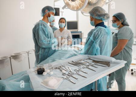 Konzentriertes Operationsteam, das mit einem Patienten in einem Operationssaal zusammenarbeitet Stockfoto