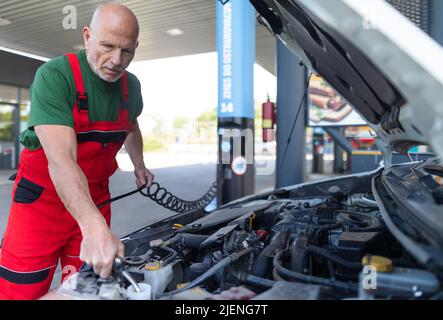 Leitender Mechaniker, der den Ölstand im Automotor überprüft. Stockfoto