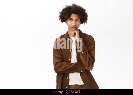 Porträt eines nachdenklichen jungen Mannes, der denkt, in seinem Kopf Entscheidungen trifft und auf weißem Hintergrund steht Stockfoto