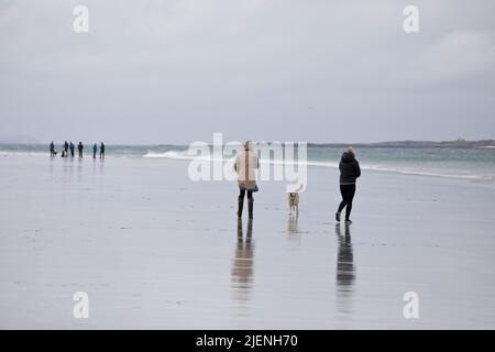 Menschen, die mit ihren Hunden am Strand von Luskentire auf der Isle of Harris, Äußere Hebriden, Schottland, Vereinigtes Königreich, spazieren gehen Stockfoto