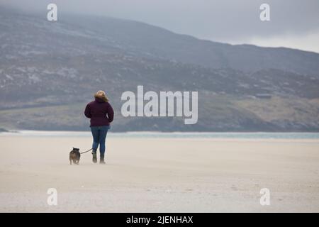 Frau mit ihrem Hund zu einem Spaziergang am Strand von Luskentire auf der Isle of Harris, Äußere Hebriden, Schottland, Großbritannien Stockfoto