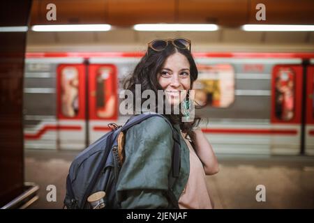 Die MittelErwachsene Pendlerin steht in der U-Bahn-Station und schaut auf die Kamera. Stockfoto