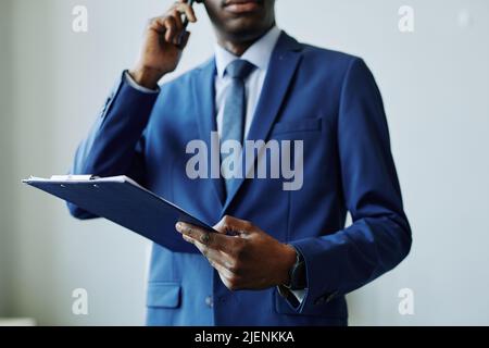 Porträt eines afroamerikanischen Geschäftsmannes, der im Büro am Telefon einen Anzug trägt Stockfoto