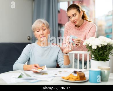 Junge Frau erhält Geld von ihrer älteren Mutter Stockfoto