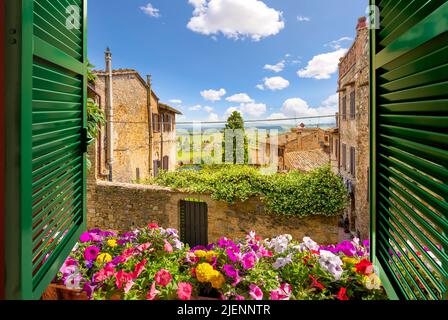 Blick durch ein offenes Fenster mit Fensterläden auf die toskanische Landschaft und die mittelalterliche Altstadt von San Gimignano, Italien. Stockfoto