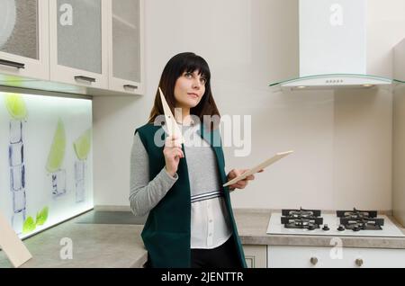 Junge Frau mit einer Holzdiele neben einem Gasherd in der Küche Stockfoto