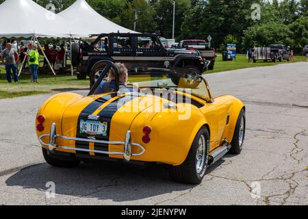 Ein Mann fährt seinen gelben AC Cobra Replik-Sportwagen auf einer Automobilausstellung in Fort Wayne, Indiana, USA. Stockfoto