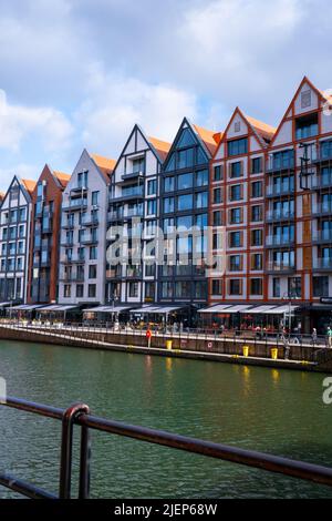 Danzig, Polen Mai 2022, moderne Gebäude über dem Motlawa-Fluss in der Altstadt. Tourismus auf dem Motlawa River. Neue Apartments-Architektur auf Granary Island Glasfenster mit Reflexionen. Touristisches Reiseziel Stockfoto