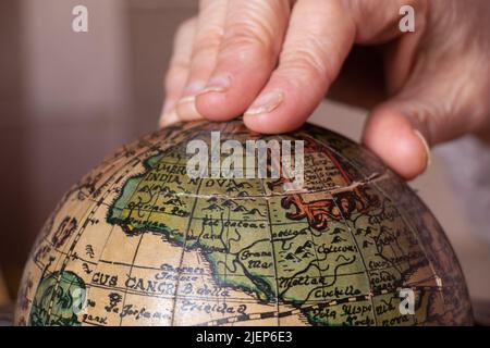 Die Hand einer Frau, die einen alten Globus aus der Nähe hält Stockfoto