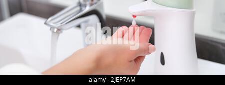 Ein Tropfen Seife aus einem Spender tropft auf die Hand einer Frau, Stockfoto