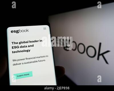 Person, die Mobiltelefon mit der Webseite des britischen Nachhaltigkeitsdatenunternehmens, der Firma, der Firma, mit dem Logo, auf dem Bildschirm hält. Konzentrieren Sie sich auf die Mitte des Telefondisplays. Stockfoto
