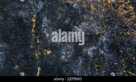 Luftdrohnen-Rundflug über schwarzer Aschefelde aus verbranntem braungelbem, trockenem Gras und weißem Rauch am sonnigen Herbsttag. Blick von oben. Textur natürlicher Hintergrund der ökologischen Umweltkatastrophe. Stockfoto