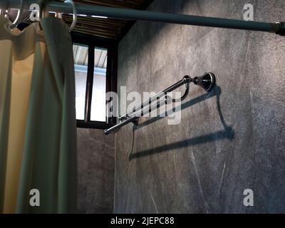 Leere lange und gebogene, zwei Stufen von Edelstahl Handtuchhalter Rack auf Luxus grauen Betonfliesen Wand in der Nähe des Fensters in der Dusche Bad. Stockfoto
