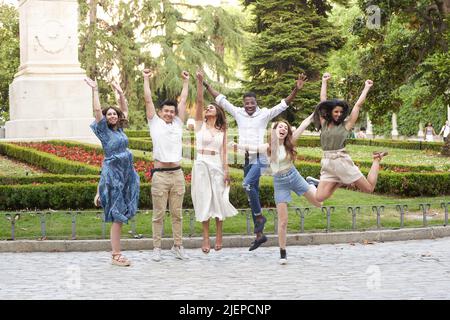 Gruppe multiethnischer Freunde, die lächeln und springen, während sie gemeinsam im Park Spaß haben. Freundschaftskonzept. Stockfoto