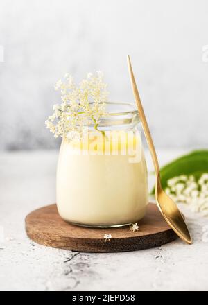 Hausgemachtes Elder Flower Dessert Panna Cotta, Mousse oder Pudding in einem Portionsglas mit Zitronenquark und frischen Blumen. Speicherplatz kopieren. Stockfoto