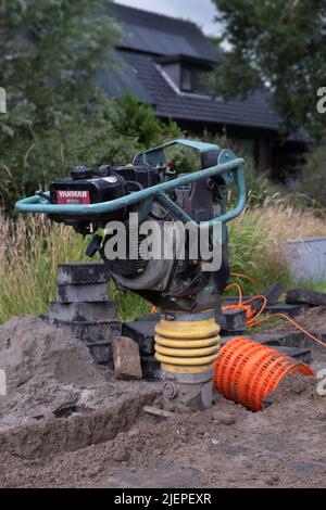 Tragbarer Vibrationsstampfer oder Vibrationsstampfer zum Stoppen des Sandes, bevor die Pflastersteine darauf gelegt werden Stockfoto