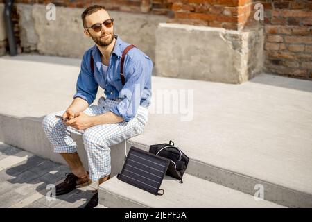 Mann laden Telefon von tragbaren Solarpanel Stockfoto