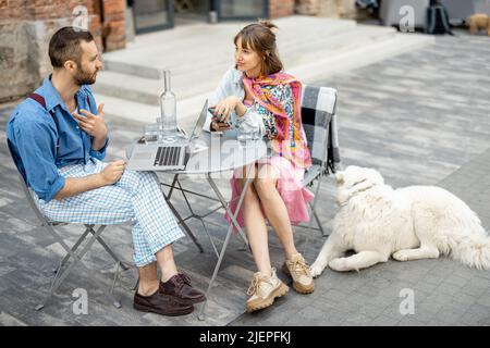 Stilvolles Paar Kollegen unterhalten sich, sitzen mit Hund im Café Stockfoto