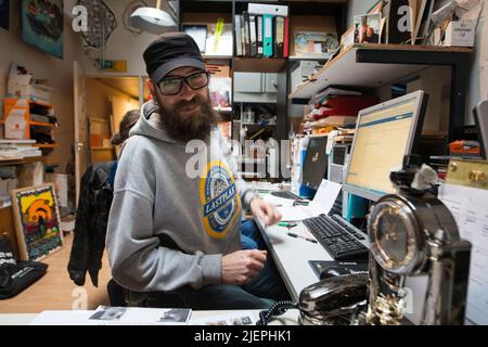 Rotterdam, Niederlande. Multi Artist Herr Milan Tilder hinter seinem Schreibtisch und Computer als Chief Coordinator der Via Kunst, einer religiösen Wohlfahrtsorganisation, die Teil der Duch Reformierten Pauluskerk (Kirche des Paulus) ist. Via Kunst ist eine Stiftung, die Obdachlose Street Artist und Menschen unterstützt, die soziale und metallische Unterstützung benötigen. Stockfoto