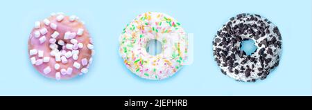 Drei leckere Donuts auf hellblauem Hintergrund. Draufsicht Stockfoto