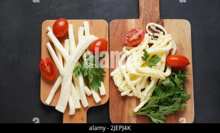 Streichkäse oder Käsepeitsche - salziger Snack-Käse mit Kirschtomaten und Kräutern auf Schneidebrett. Türkischer Käse Stockfoto