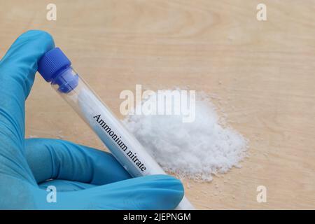 Ammoniumnitrat im Reagenzglas und Holzhintergrund Stockfoto