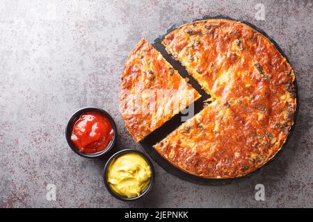 Hausgemachter knuspriger Cheeseburger-Kuchen mit Saucen aus der Nähe auf einem Schieferbrett auf dem Tisch. Horizontale Ansicht von oben Stockfoto