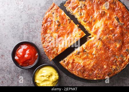 American Cheeseburger Pie mit Hackfleisch und Cheddar-Käse aus der Nähe auf einem Schieferbrett auf dem Tisch. Horizontale Draufsicht von oben Stockfoto