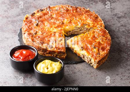 Köstliche beliebte Fleisch Cheeseburger Pie serviert mit Saucen Nahaufnahme auf einem Schieferbrett auf dem Tisch. Horizontal Stockfoto