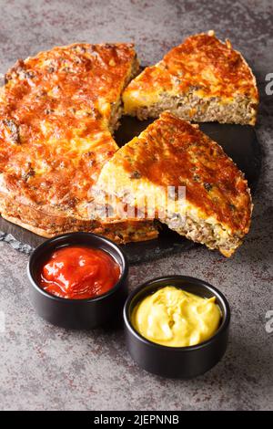 American light Cheeseburger Pie serviert mit Saucen Nahaufnahme auf einem Schieferbrett auf dem Tisch. Vertikal Stockfoto