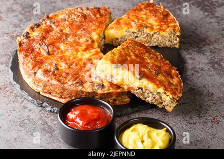 American Cheeseburger Pie mit Hackfleisch und Cheddar-Käse aus der Nähe auf einem Schieferbrett auf dem Tisch. Horizontal Stockfoto